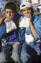 Two gypsy boys sniffing glue from plastic bags