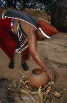 Zulu woman preparing fire for firing pot.