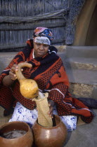 Basotho woman pouring beer into a strainer from a gourd