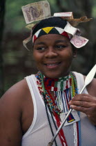 Zulu woman holding a spear with money attached to head wear symbolic of her transition to womanhood