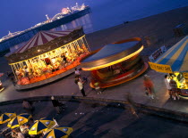 England, East Sussex, Brighton, Carousel at night on the seafront with the Pier illuminated in the background.