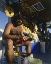Kardamina fisherman cleaning sponges at his natural sea products stall