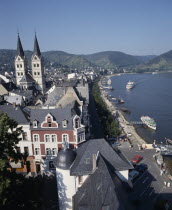 Town beside River Rhine. Building with twin towers. Boats moored at pontoons.