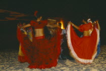 Women in costume dancing on the beach at night