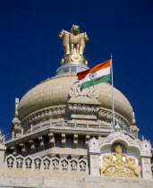 Vidhana Soudha building.  Exterior detail of roof dome  crest  flag and gold statue on top.  Built in 1954 housing the Secretariat and the State Legislature.