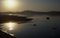 View over Irawaddy river at dusk or dawn with the sun in left corner reflecting off water Bagan Burma