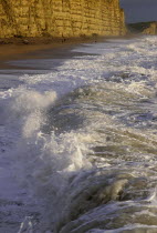 Chesil Bank with waves breaking on the pebble beach below the cliffs