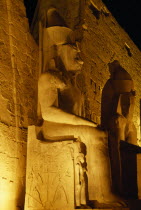 The temple illuminated at night with the giant statues of Ramesses II outside The Pylon