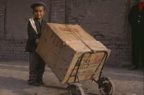 Child pushing a box on two wheeled trolley