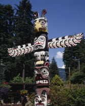 Stanley Park a close up of the top of a Totem pole with gardens behind