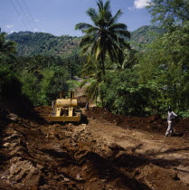 Bansal road repairing after heavy rain using Caterpillar bulldozer  tarmac road coconut palm  trees & terraced fields behind. Lombok Barat  NTB J 6574