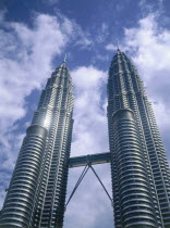 Looking up towards The Petronas Towers with a lightly clouded sky behind
