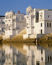 White temple on shore of Pushkar Lake and reflected in water.