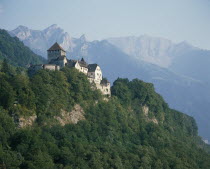 The Castle nestling in  wooded hillside  rugged mountains behind
