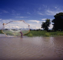 Boy casting fishing net into lake