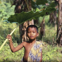 Boy with a sarong over his shoulder using a large leaf as sun shade