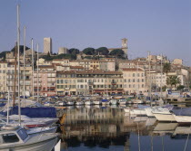 Cannes castle above the harbour buildings with boats moored in the foreground