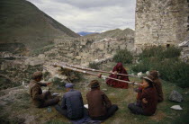 Men blowing long horns on a hillside at Ganden Monastery