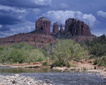 Cathedral Rock in Oak Creek Canyon. View over river to wind eroded rock formation with a girl and boy playing at waters edge.