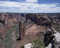 View looking down to Spider Rock with canyon beyond and scree slopes. A path cuts through canyon floor.