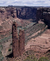 View looking down to Spider Rock with canyon beyond and scree slopes. A path cuts through canyon floor.