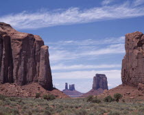 The North Window View through rock features to isolated mesa and pinnacles with scree slopes and scrub.