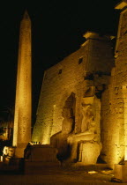 The temple illuminated at night seated statues of Ramesses II outside the Pylon with the Obelisk