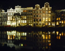 Canalside houses and lights reflected in water at night.