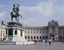 Hofburg Palace. Equestrian statue on plinth standing in courtyard outside semi circular facade with passing people.