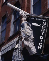 Moby Dickhanging sign with ships figurehead on a brick building