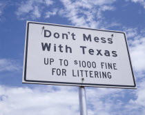 Sign reading Dont Mess with Texas with light cloud and blue sky beyond