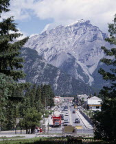 Banff Avenue the main straight street with a mountain peak behind seen between pine trees