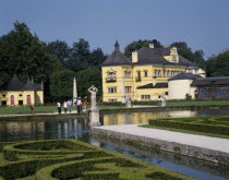 Hellbrunn Palace  a yellow building behind an ornamental lake rimmed with boxed hedges
