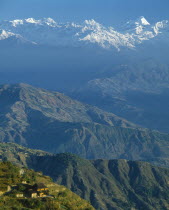 Mountain village on lower slopes with distant snow covered peaks beyond.