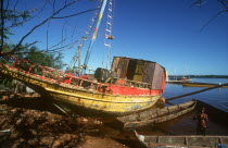 Beached fishing boat with boy in shallow water