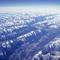 The snow covered Rocky Mountains with a thin layer of cloud seen from above