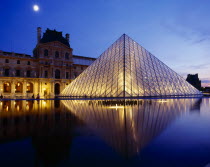 Louvre.  Glass pyramid and surrounding buildings floodlit at night and reflected in water in the foreground.