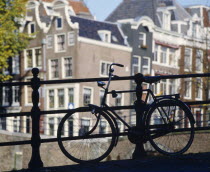 Bike parked against railings with traditional architecture behind.