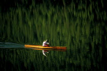 Single canoeist on lake with reflection of trees in the water near Kalispell