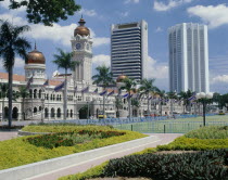 Sultan Abdul Samad building with its copper domes and skyscrapers beyond  with flower beds in the foreground