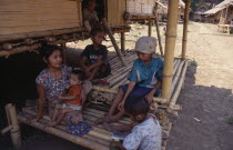 Karen refugee mother feeding child with four other children sitting in the shade