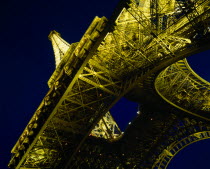 Eiffel Tower.  Angled view from below floodlit at night.