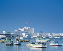 Fishing boats moored in harbour with fortress castle and walls beyond.