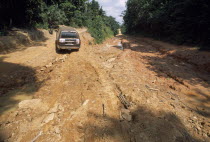 Car on unmade road with deep ruts through mud in foreground.   Automobile  Automobile