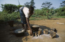 Young woman cooking on open wood fire.