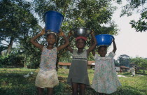 Three children carrying water vessels on their heads.