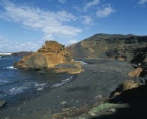 El Golfo.  Black volcanic sand beach and coastline with a few people sunbathing or walking along shore.