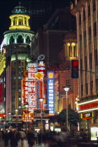 Nanjing Road at night with illuminated neon signs and crowds of people in blurred movement below.