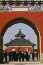 Temple of Heaven.  Temple and tourists framed by red painted archway. Peking
