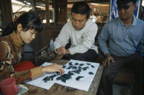 Jade traders examining cut pieces in central jade market.Burma Myanmar